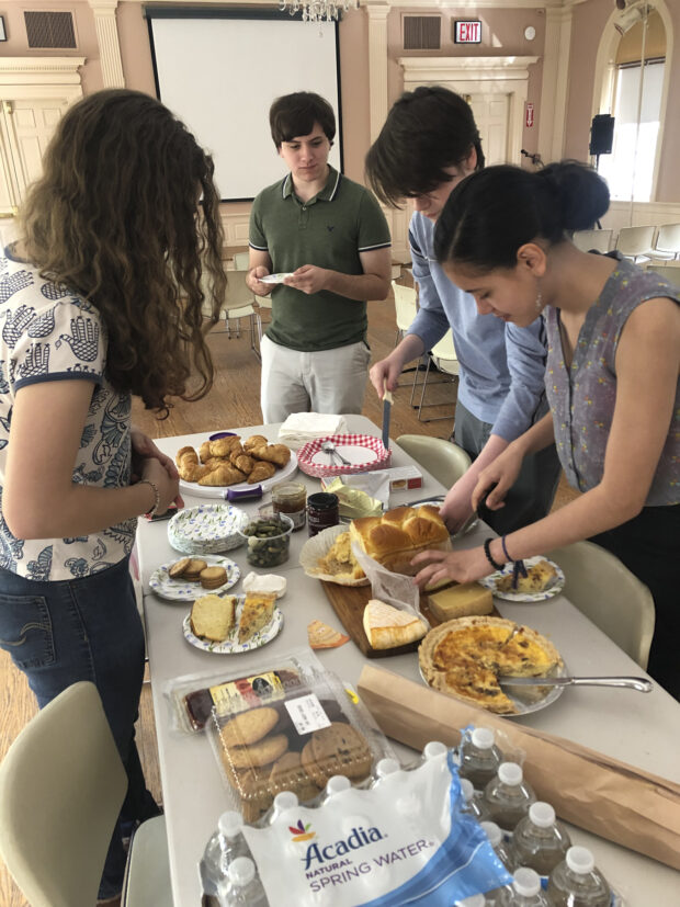 Une fête française (A French feast) Students gather around a table full of French food.