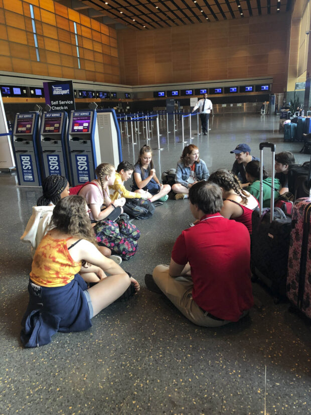 Students sitting in a circle on the floor at at Logan International Airport in Boston.