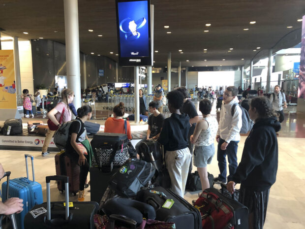 Students wait for their luggage by the baggage carousel at the Charles de Gaulle Airport.